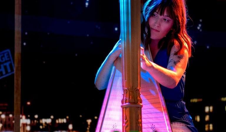 A harpist performing under colorful lights with a city nightscape in the background.
