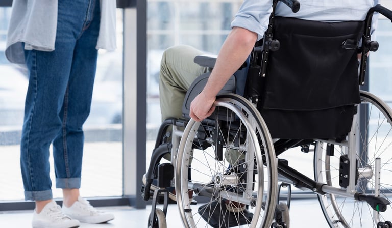 duas pessoas conversando uma mulher em pé e um homem em cadeira de rodas