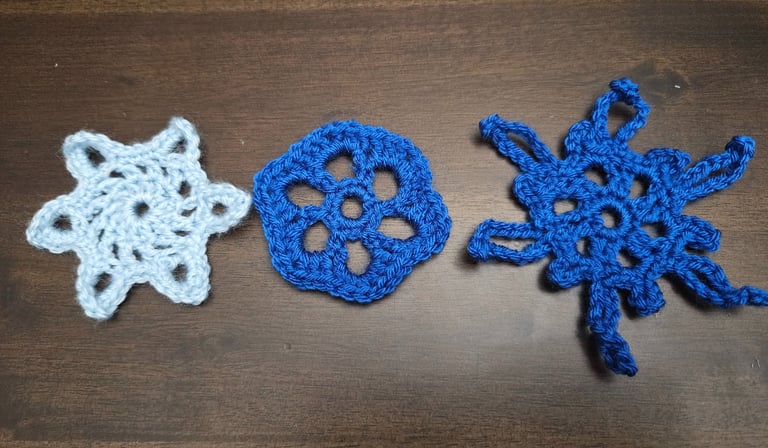 three crochet snowflakes on a wooden table