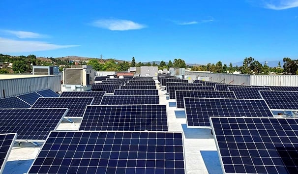 A wide commercial rooftop solar panel installation under a clear blue sky for renewable energy.