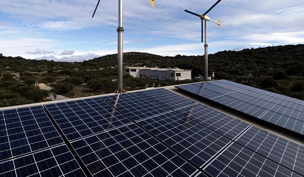 Rooftop solar panel array and small wind turbines providing renewable energy to a rural building.