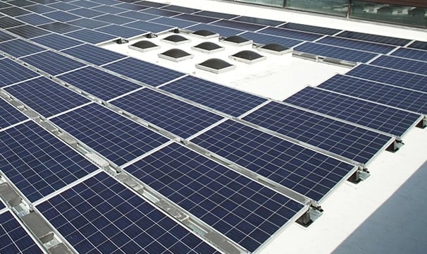 Commercial rooftop solar panel installation with rows of photovoltaic modules and skylights.