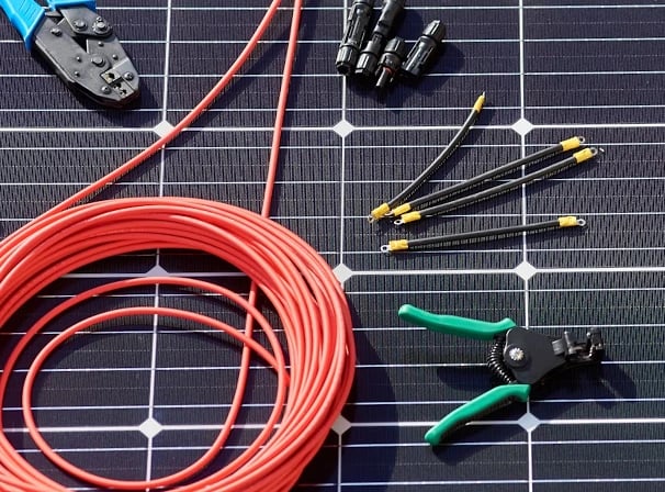 Solar panel installation tools including wire crimpers, cable strippers, and connectors on a monocrystalline solar module.