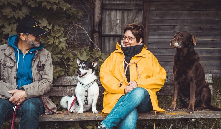 Marion & Martin Lindhof sitzen mit 2 Hunden auf einer Bank.