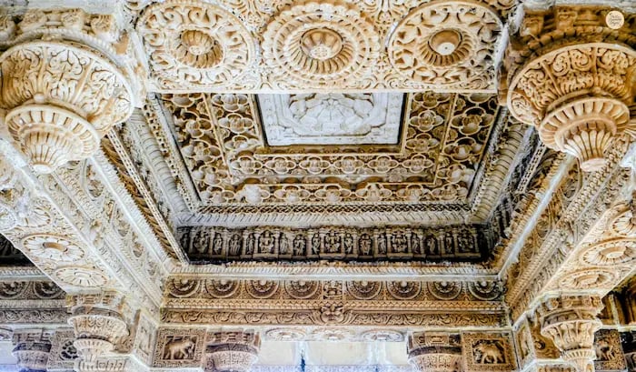 Detailed ceiling carvings inside a cenotaph at Nau Chauki Pal showcasing fine marble craftsmanship.