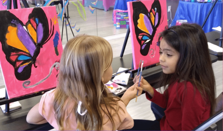 two little girls painting a butterfly on a canvas
