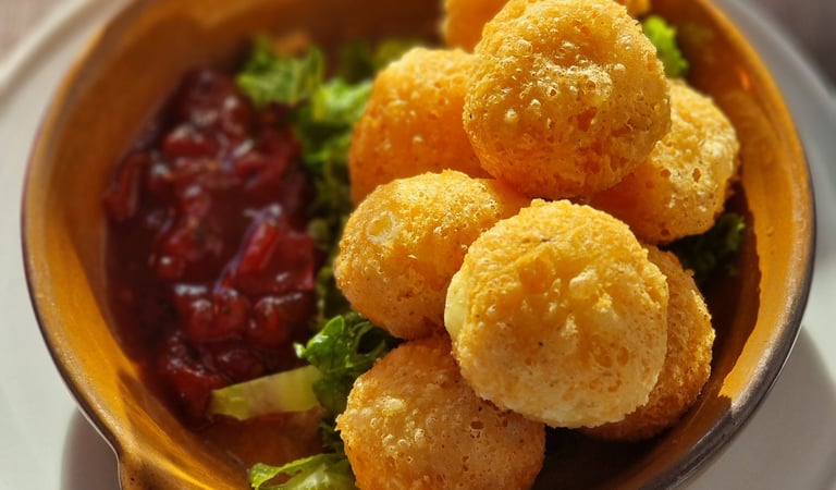 Golden fried breaded brie cheese balls served with a sweet cranberry dipping sauce and garnish.