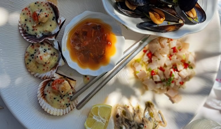 Fresh seafood platter with grilled scallops in shells, steamed mussels, ceviche, and lemon wedges.