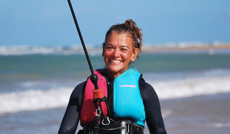 a woman in a wetsuit connecte a kitesurf
