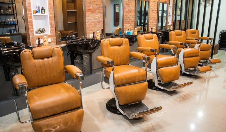 Modern salon interior featuring tan leather styling chairs and brick walls.