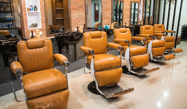 Modern salon interior featuring tan leather styling chairs and brick walls.