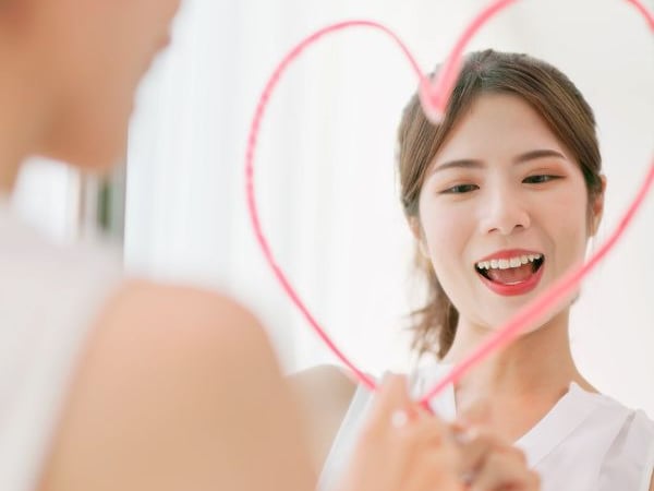 a woman drawing a heart on a mirror