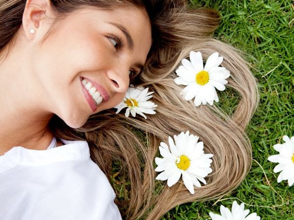 woman laying in the grass with daises beside her