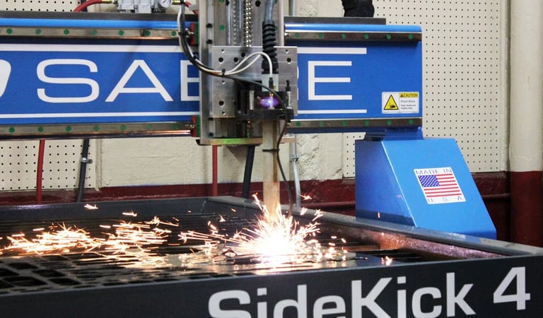 A Sabre SideKick 4 CNC plasma cutter sparks while cutting metal in a workshop.