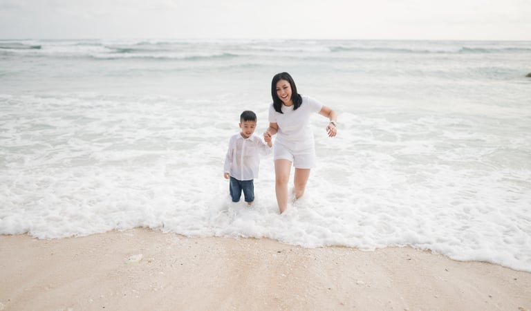 Parents and child standing near the shoreline of Melasti Beach Bali during a natural family photography session