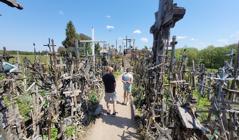 Guide Simas walking with tourists through the Hill of Crosses pilgrimage site in Lithuania .