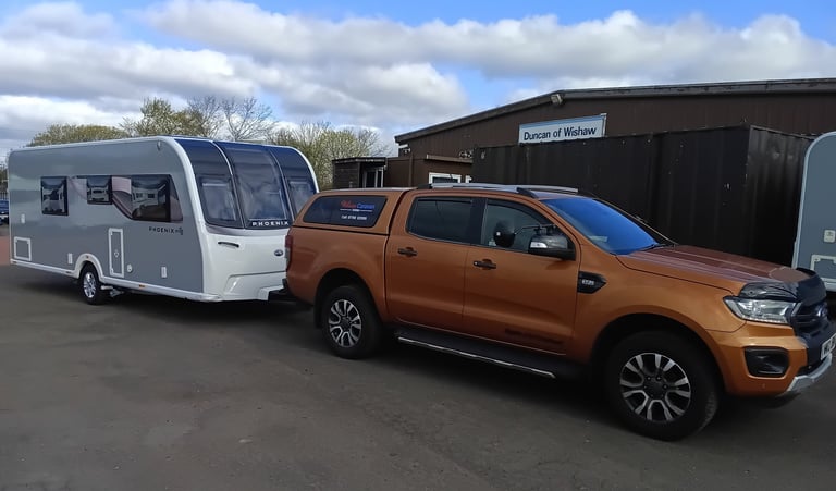 Orange Ford Ranger pickup truck towing a white Bailey Phoenix caravan at Duncan of Wishaw.