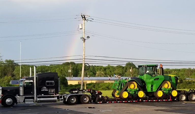 a tractor trailer with a rainbow - colored rainbow in the background