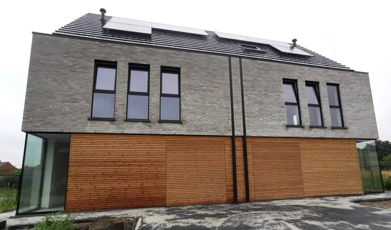 Een huis met een dak met zonnepanelen en een houten omheining.