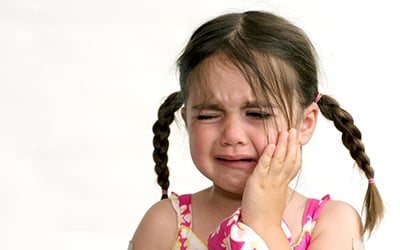 a child crying with keeping hands on cheeks dueto toothache