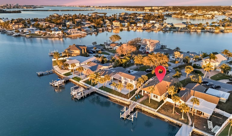 Aerial view of waterfront real estate in Florida with a red location pin marking a luxury home.