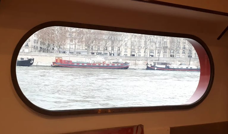 Vue du fleuve à travers un sabord oblong sur une péniche à Paris