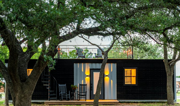 Una pequeña casa contenedor negra con terraza y cubierta.