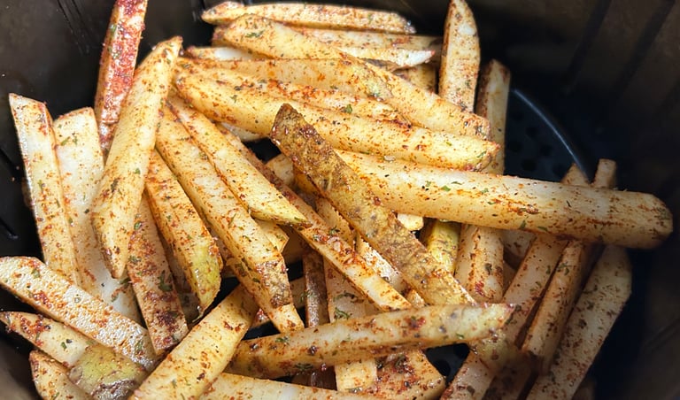 Seasoned uncooked fries inside an air fryer pan.
