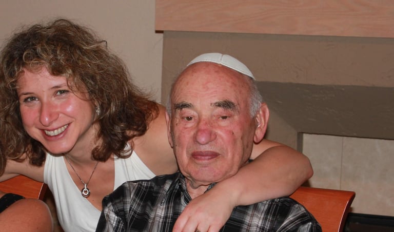 A smiling woman hugging an elderly man wearing a white yarmulke at a family gathering.
