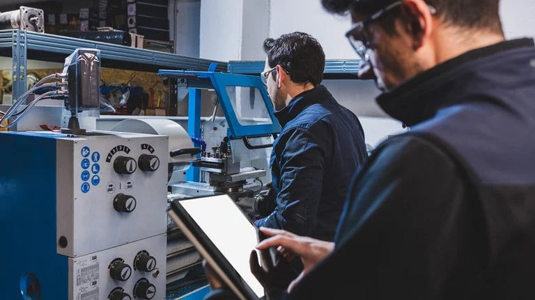 Pracownicy fabryki produkują części metalowe używając maszyny cnc
