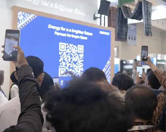 Mass crowd scanning QR code on large LED screen for simultaneous game participation at corporate gat