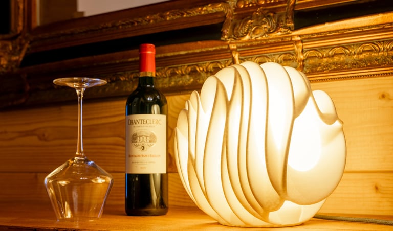Elegant modern wave lamp glowing next to a bottle of Chanteclerc red wine and an upside-down glass.
