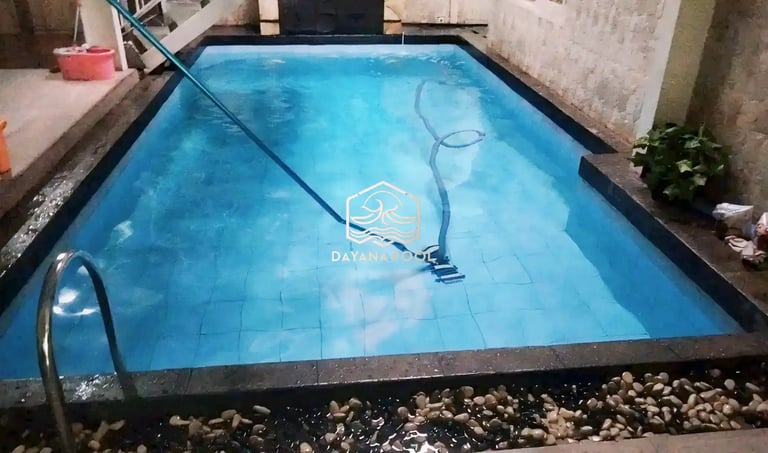 Pekerja sedang membersihkan kolam renang dengan vakum.