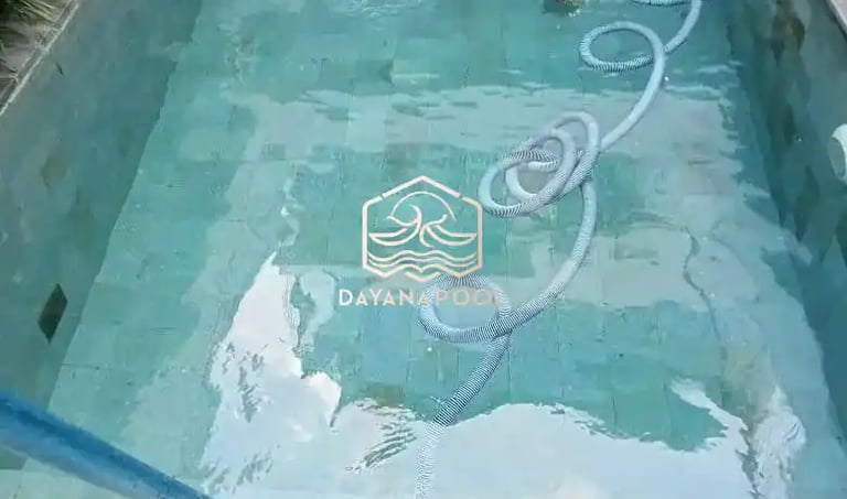 Pekerja sedang membersihkan kolam renang dengan vakum.