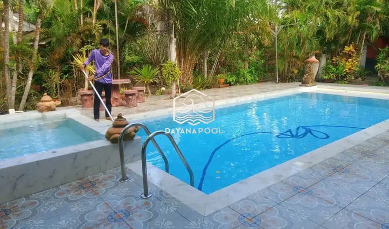 Pekerja sedang membersihkan kolam renang dengan vakum.