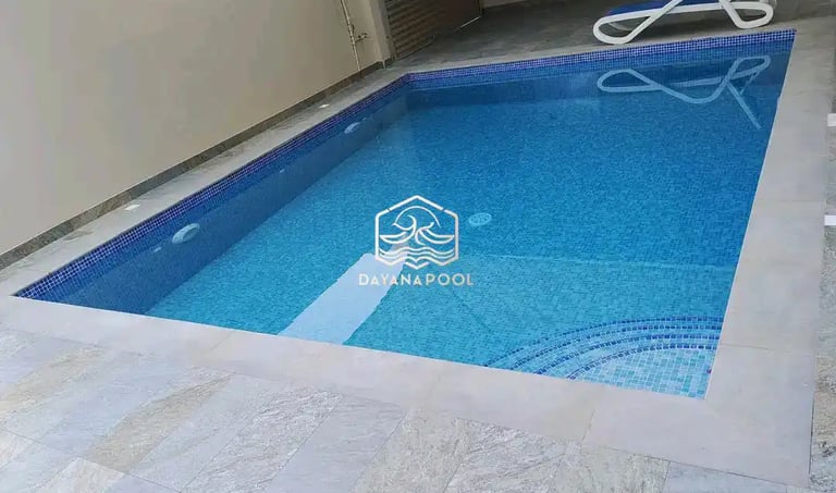 Pekerja sedang membersihkan kolam renang dengan vakum.