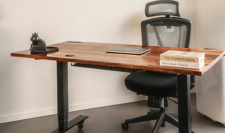 A chair behind a desk with a closed laptop, books, and old-style phone.