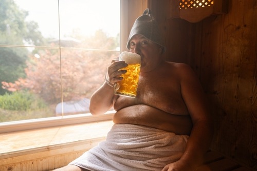 a man in a bathrobe with a glass of beer in a sauna