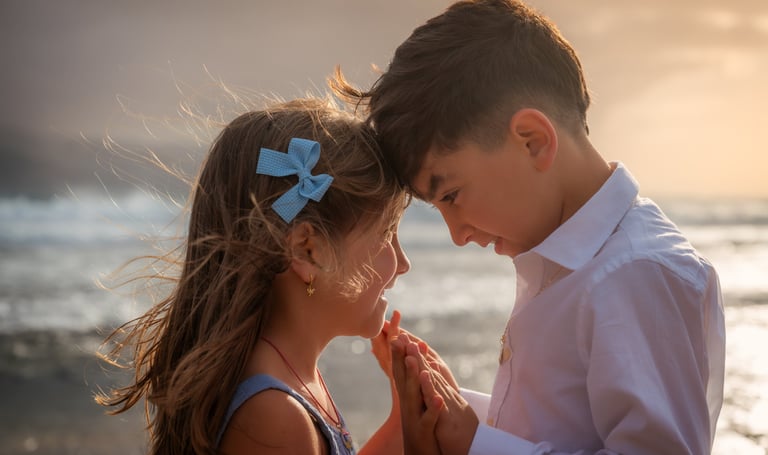 a boy and girl standing in front of a body of water