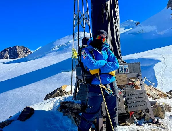 mais alhajri standing at a snowy mountain summit wearing blue climbing gear