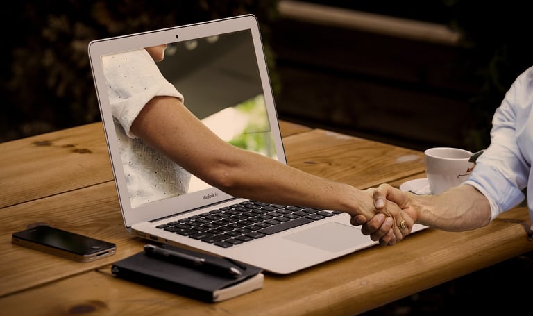 a man and woman shaking hands over a laptop