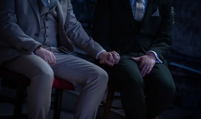 two grooms sitting holding hands