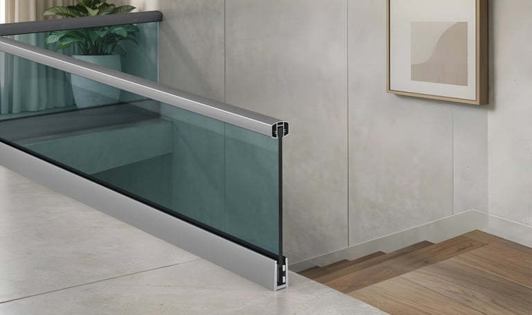 Modern interior glass railing system with aluminum handrail and base shoe for indoor stairs.