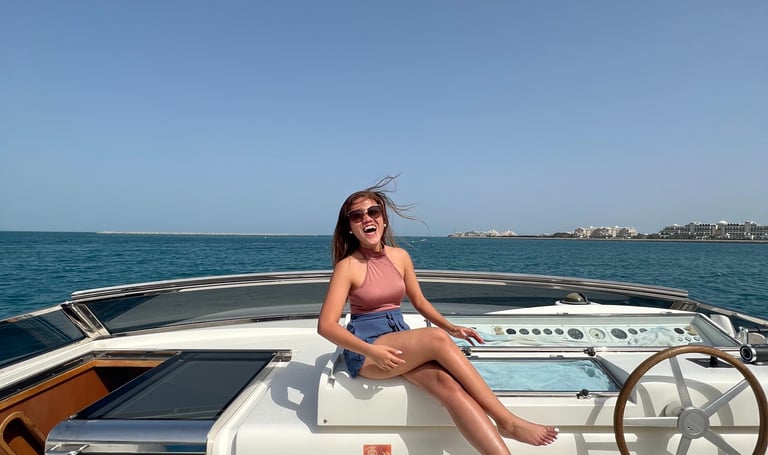a woman sitting on a boat yacht in the ocean in dubai