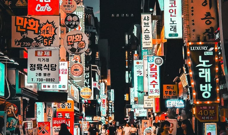 Vibrant night scene of a crowded Seoul street filled with glowing neon Korean business signs and pedestrians.
