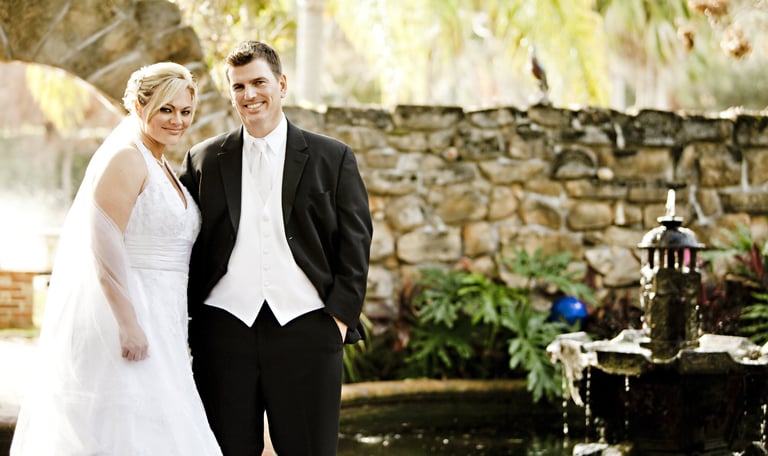 a bride and groom standing in front of a fountain