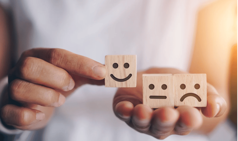 una persona che ha in mano dei cubetti di legno con sopra delle emoticon