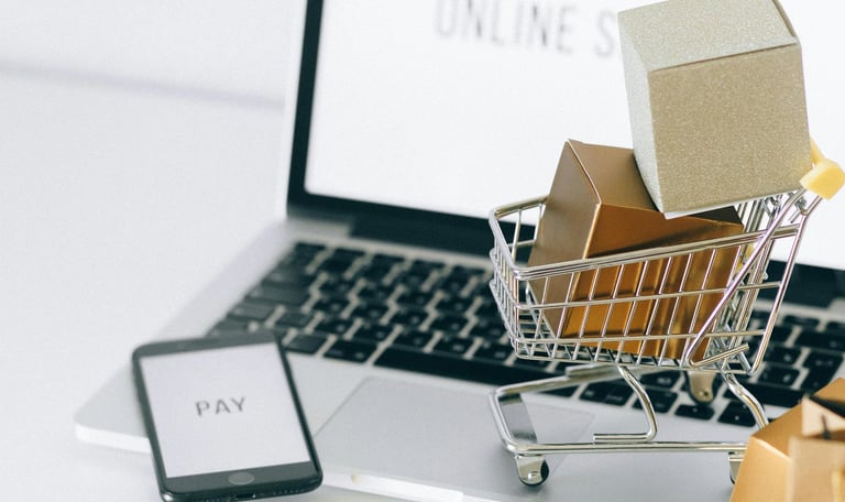 Laptop with a miniature trolley of boxes representing online shopping