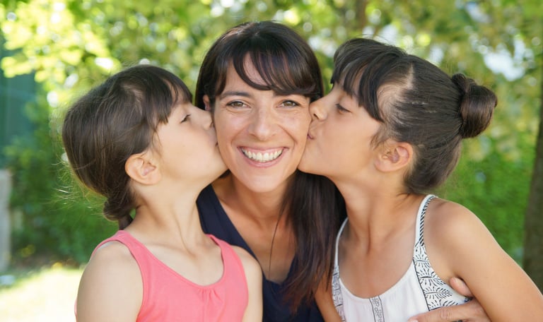 photo de famille avec deux filles embrassant leur mère.