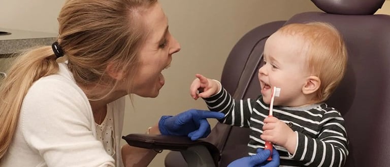 Child holding tooth brush with dentist